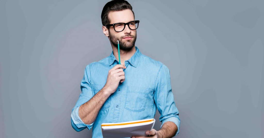 A young man wearing spectacles and holding pen and notebook, thinking to do things during coronavirus quarantine period