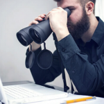 A student looking for IELTS Classes in Ludhiana on Laptop using a Binoculars