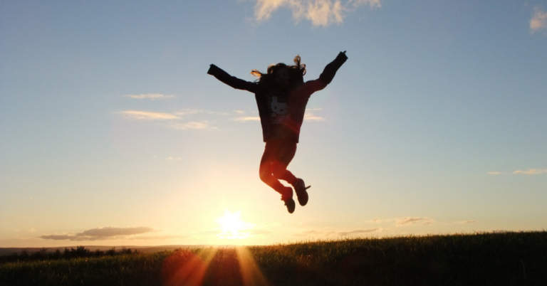 A youngster getting motivated and jumping seeing the sunrise