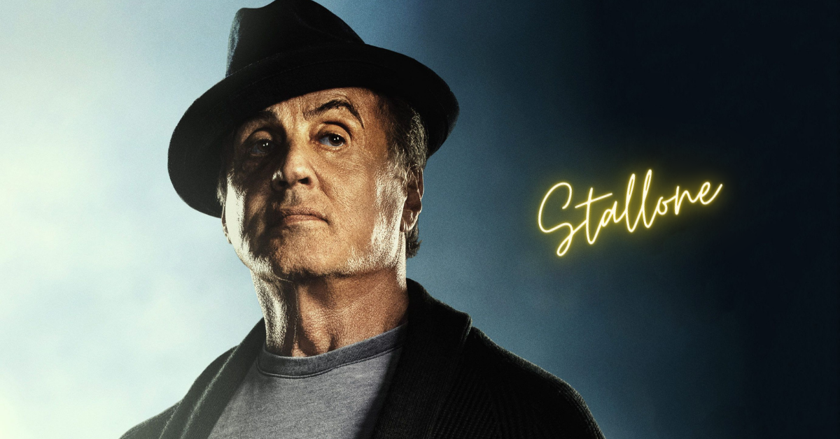 sylvester stallone standing and wearing a black hat